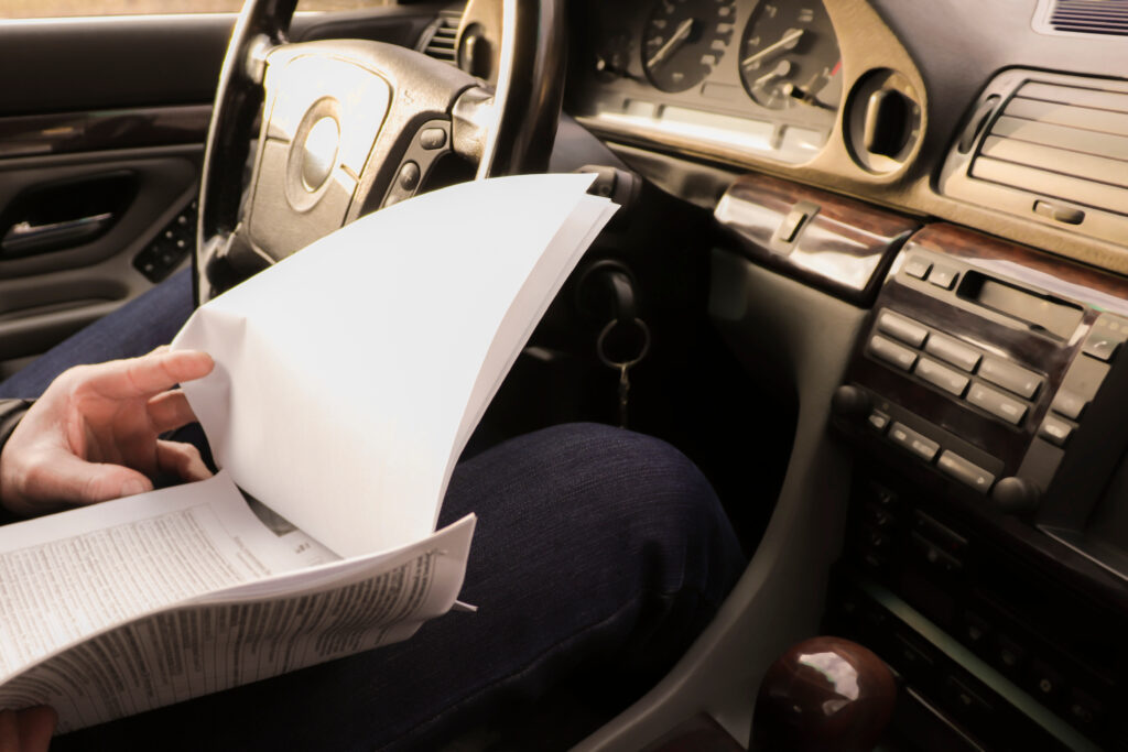 Image of a person inside of a car, looking on documents for pre purchase car inspection victoria